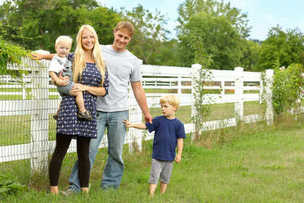 Family standing by their white wooden fence.