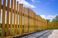 Wooden fence along a path under a blue sky